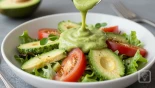 Avocado dressing over een kleurrijke salade.