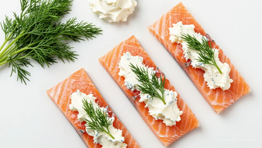 Zalm en roomkaasmengsel op een witte ondergrond.